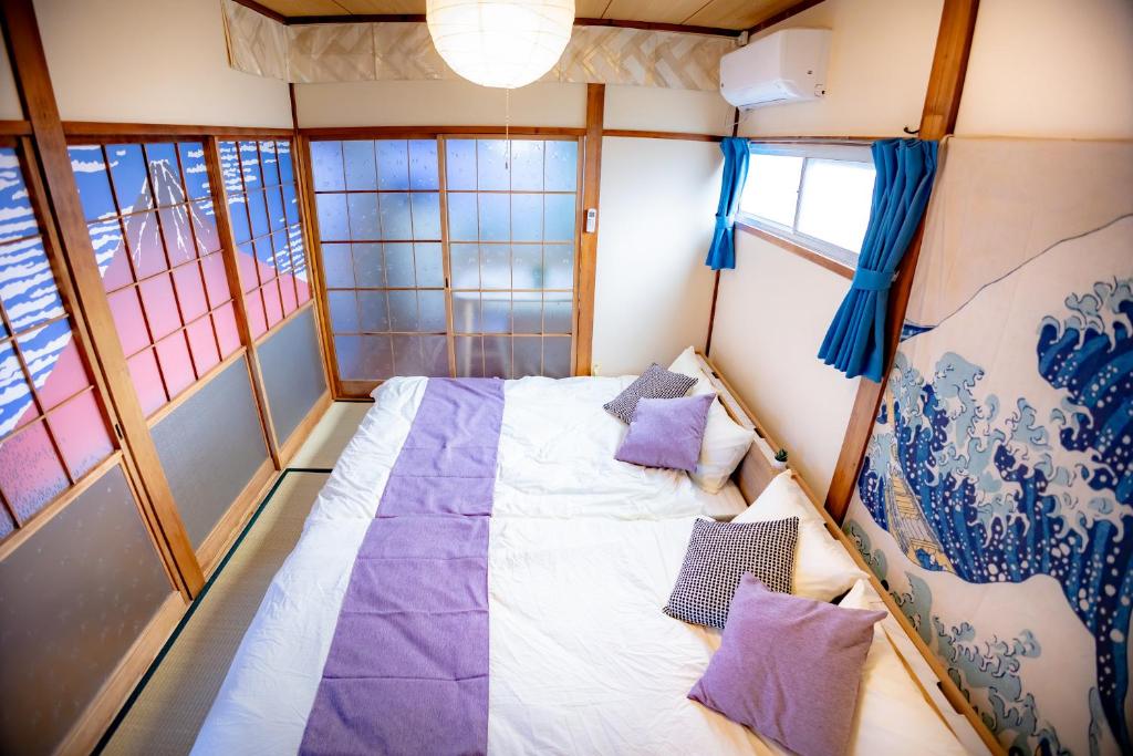 ein kleines Zimmer mit einem Bett mit lila Kissen in der Unterkunft Voyager Inn in Tokio