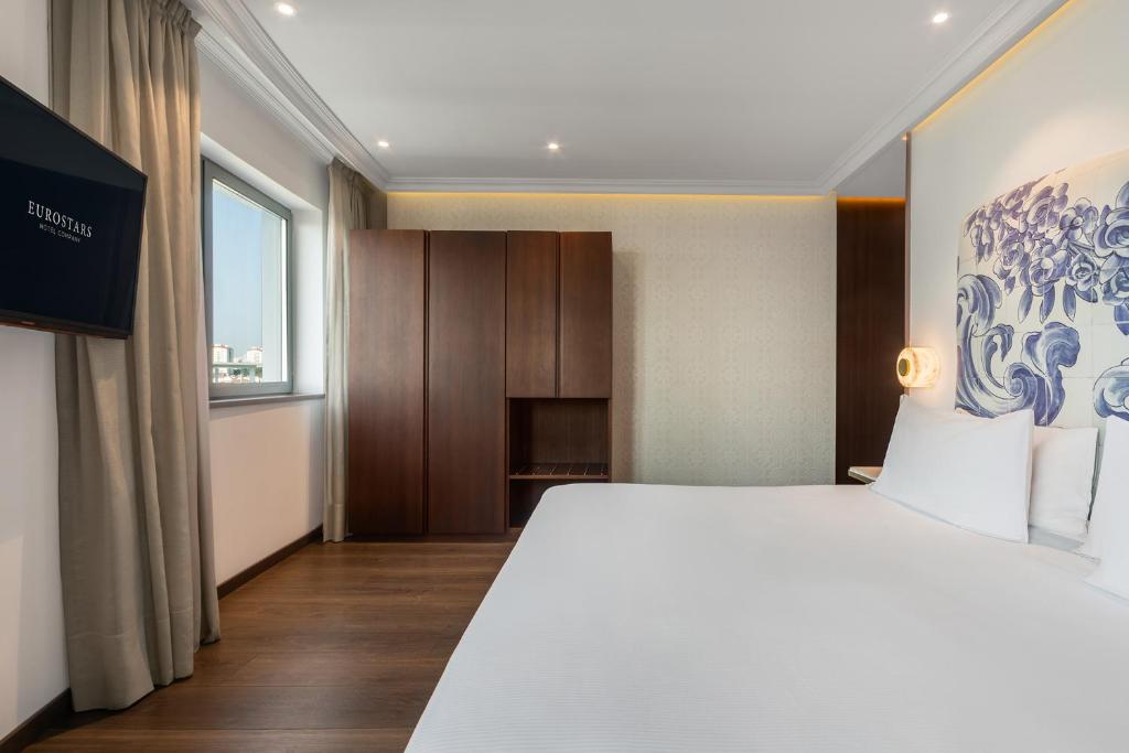 A large-bed room with a wardrobe, television and a window beside the bed.