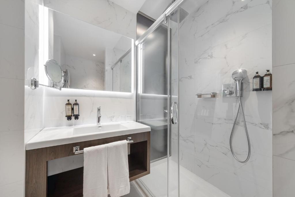 A marble-look bathroom with a floating vanity, illuminated mirror and enclosed shower.