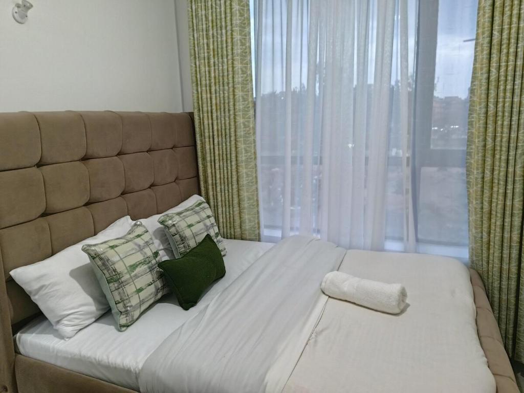 ein Schlafzimmer mit einem großen Bett mit Kissen und einem Fenster in der Unterkunft Ellber Homes in Nairobi