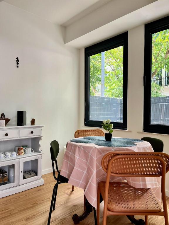 a dining room with a table with chairs and two windows at Cobalto 2 Quartos Parque Cidade Pet Friendly in Aveiro