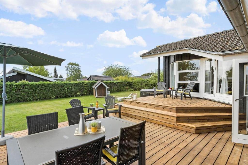 a wooden deck with chairs and a table and an umbrella at 30465-Odder-Stakket-Torn-9 in Odder