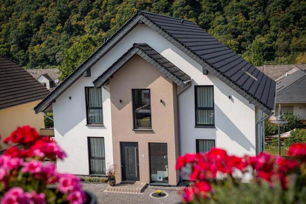 una casa con fiori rossi davanti di Genießen- Entspannen- Wohlfühlen-Komfortable Ferienwohnungen - Weingut Erich Serwazi a Mesenich