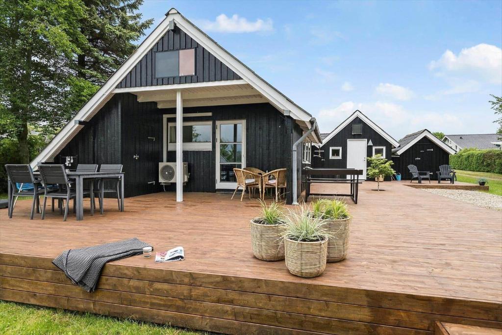 a black house with a deck with a table and chairs at 40526-Juelsminde-Pot-Strandby-53 in Sønderby