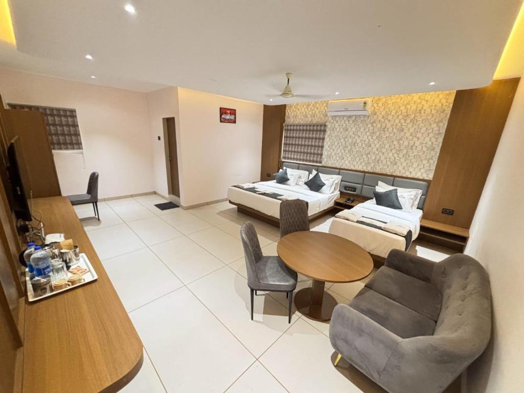 a large living room with a bed and a table at Hotel Sunrise Deluxe in Pune