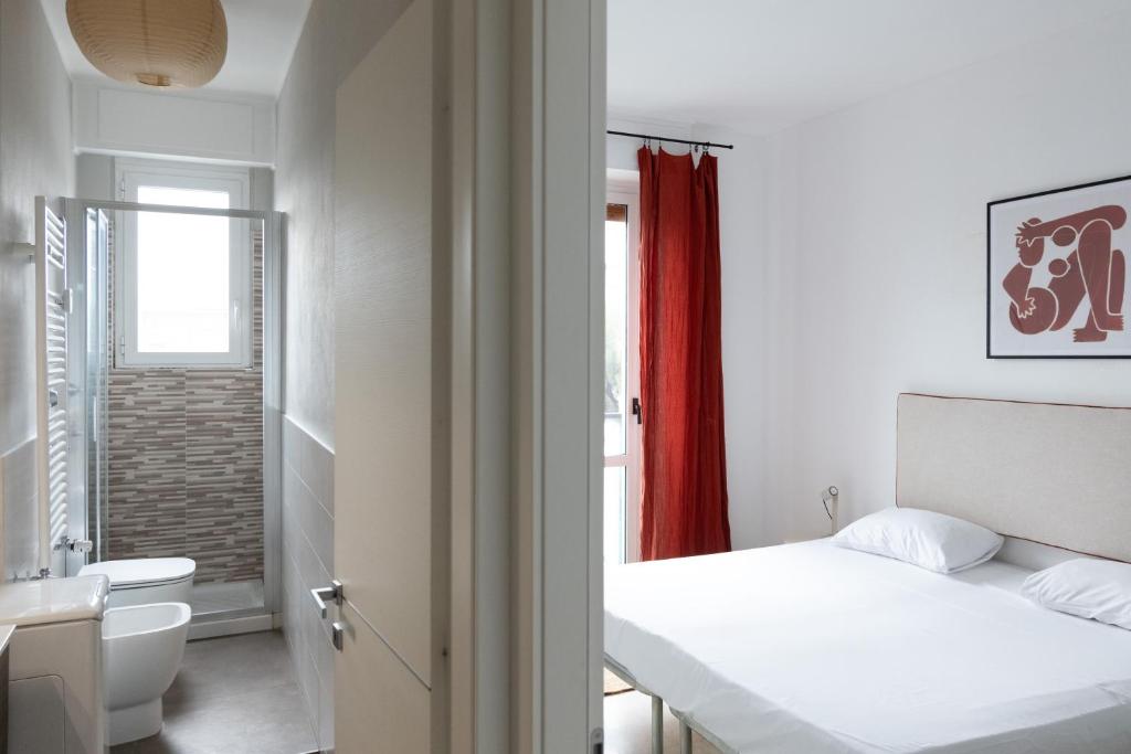 a white bedroom with a bed and a bathroom at Vivace Bilocale con vista sul Naviglio -Mirable PM in Milan