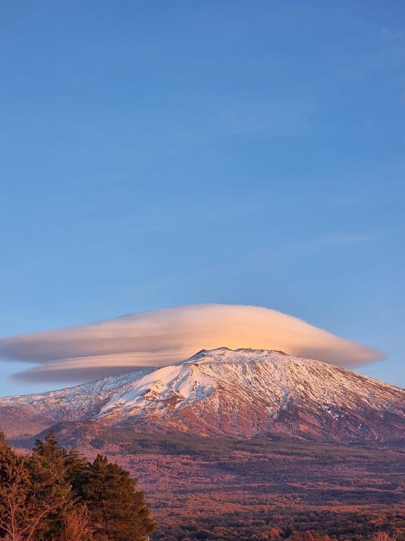 a lenticular cloud looms over a snow covered mountain at La casa di Giulia in Bronte