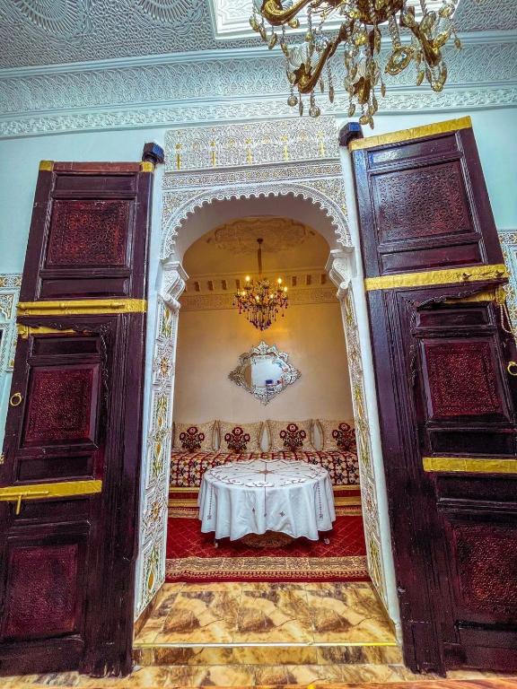 a dining room with a table in a room with a chandelier at Dar Noor Fès in Fez