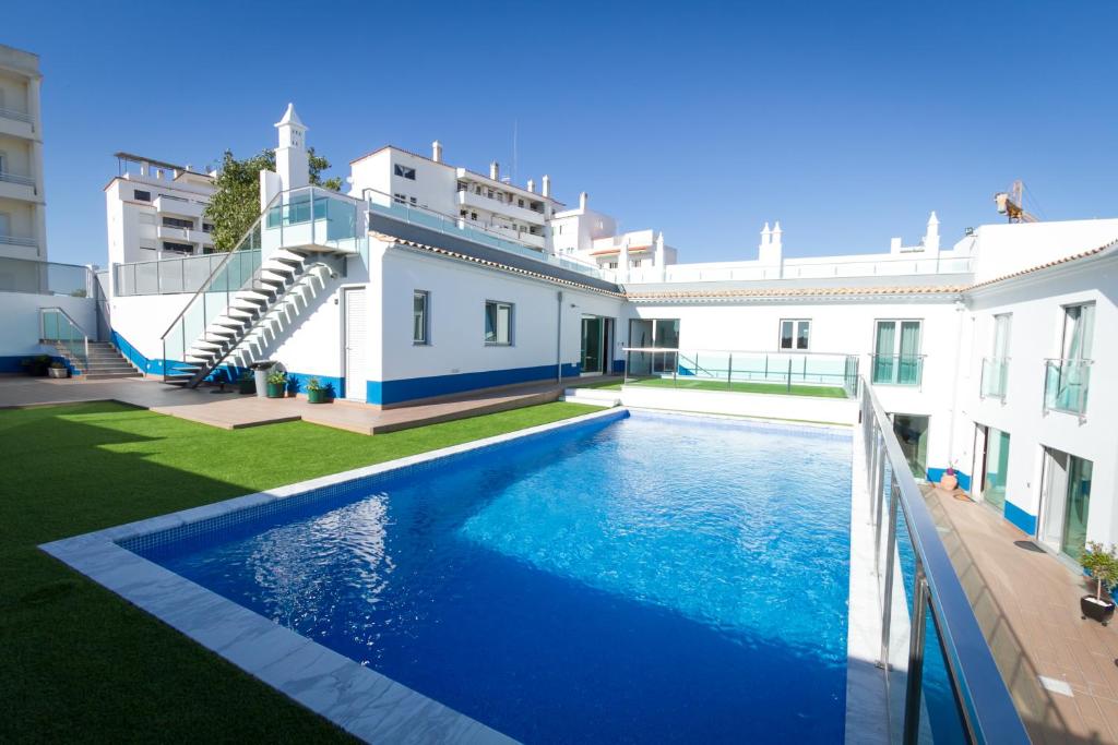 a swimming pool in front of a building with a house at PeraLux in Pêra