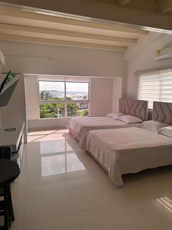 a white bedroom with a large bed and a window at Jhonny Cay Collection Apartahotel in San Andrés