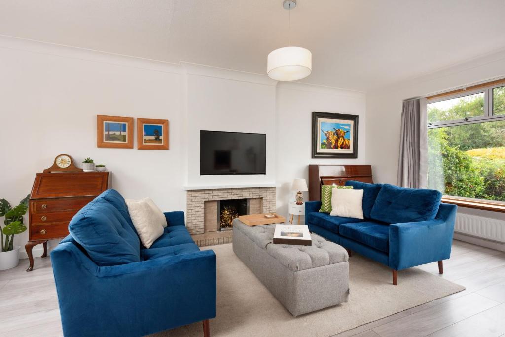 a living room with two blue chairs and a fireplace at Lawhead Road East in St. Andrews