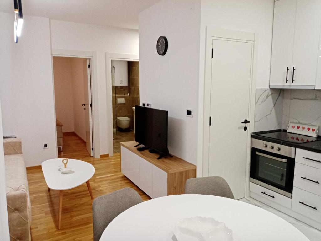 a kitchen and living room with a table and a tv at Apartman P&N Stara Pazova in Stara Pazova