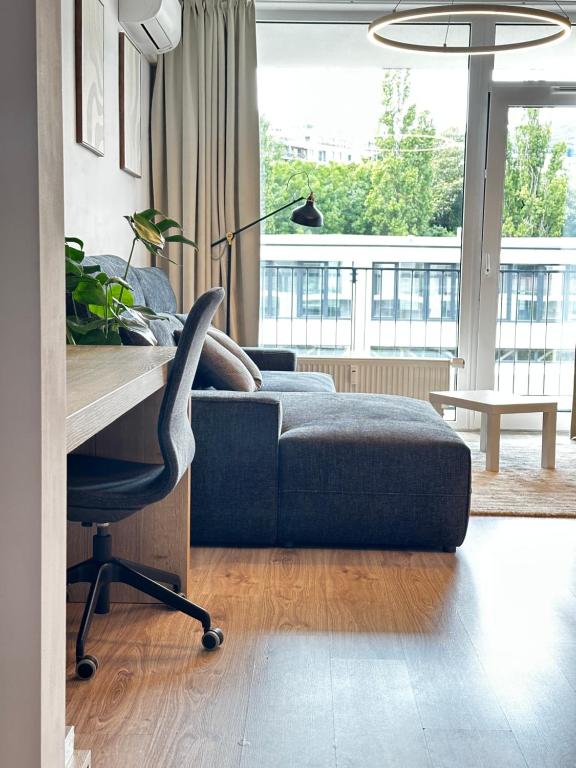 Una sala de estar con un sofá azul y un escritorio. en Hi Park Apartment, Free Parking, en Bratislava
