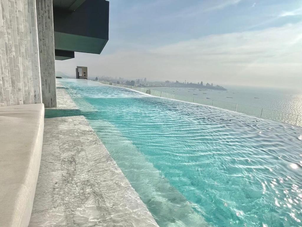 una piscina en la parte superior de un edificio junto al agua en Arom Wongamart by David Home, en Norte de Pattaya