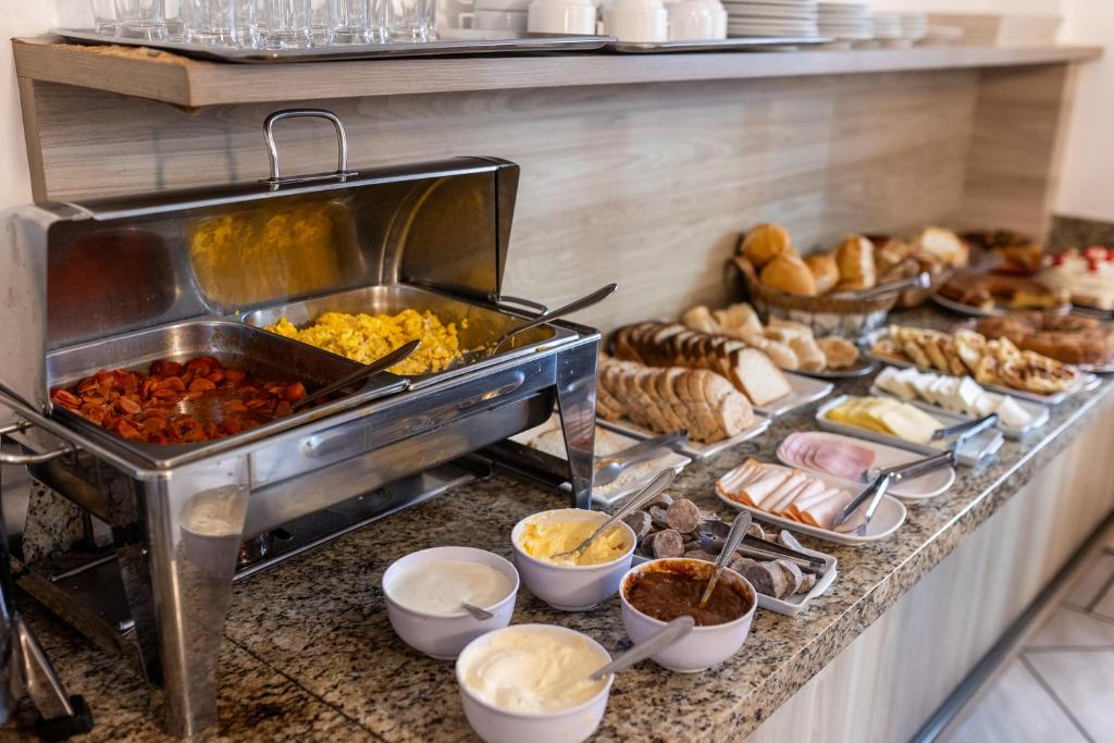 a buffet with many different types of food on a counter at Hotel Heinz in Palhoça