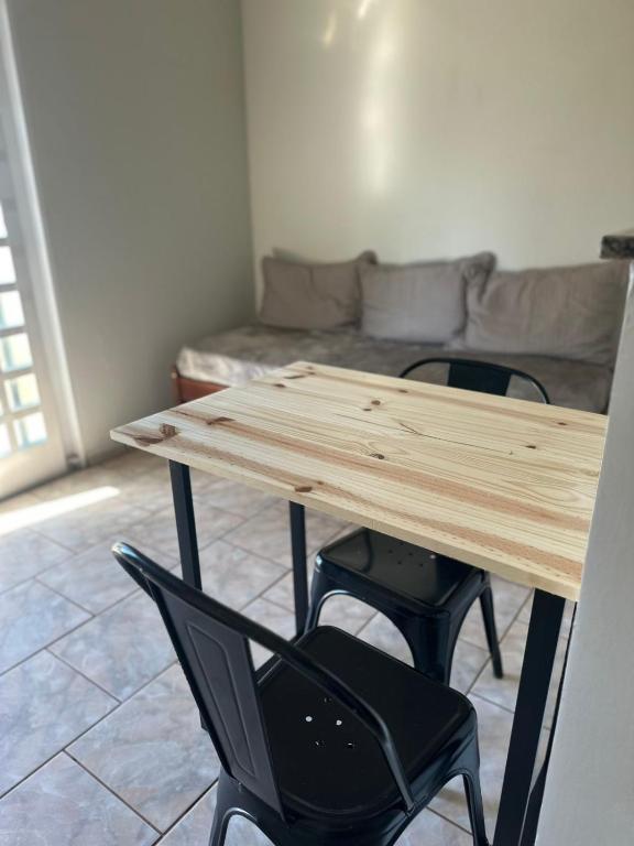 a wooden table with two chairs and a couch at Chalés no Quintal in Alvorada do Sul