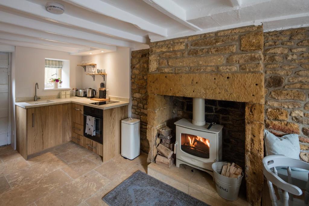 a stone fireplace in a kitchen with a stove at Middle Rose in Blockley