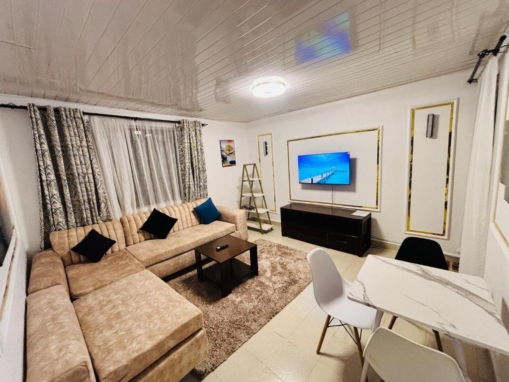 a living room with a couch and a tv at Charme Home in Nanyuki