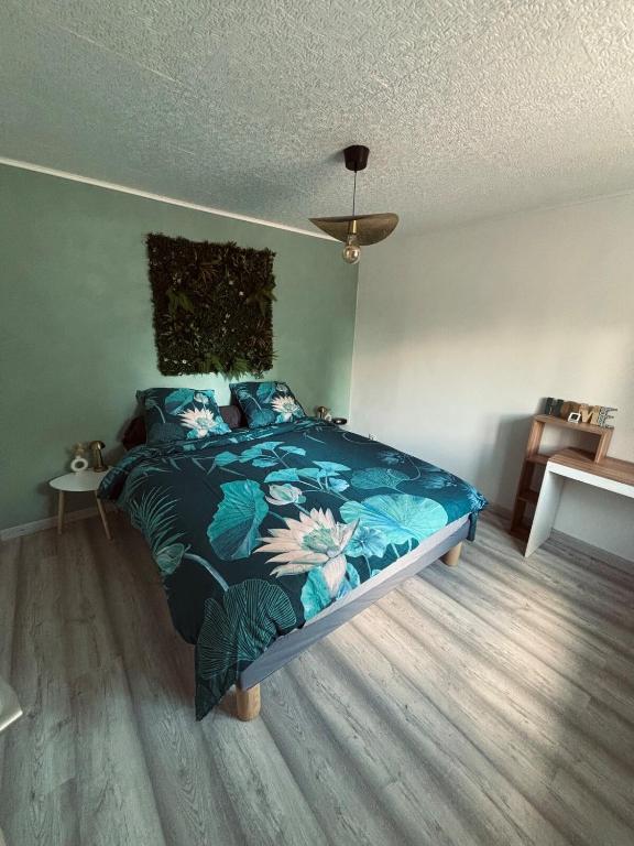 a bedroom with a bed with a blue comforter at Maison avec petite terrasse cosy 