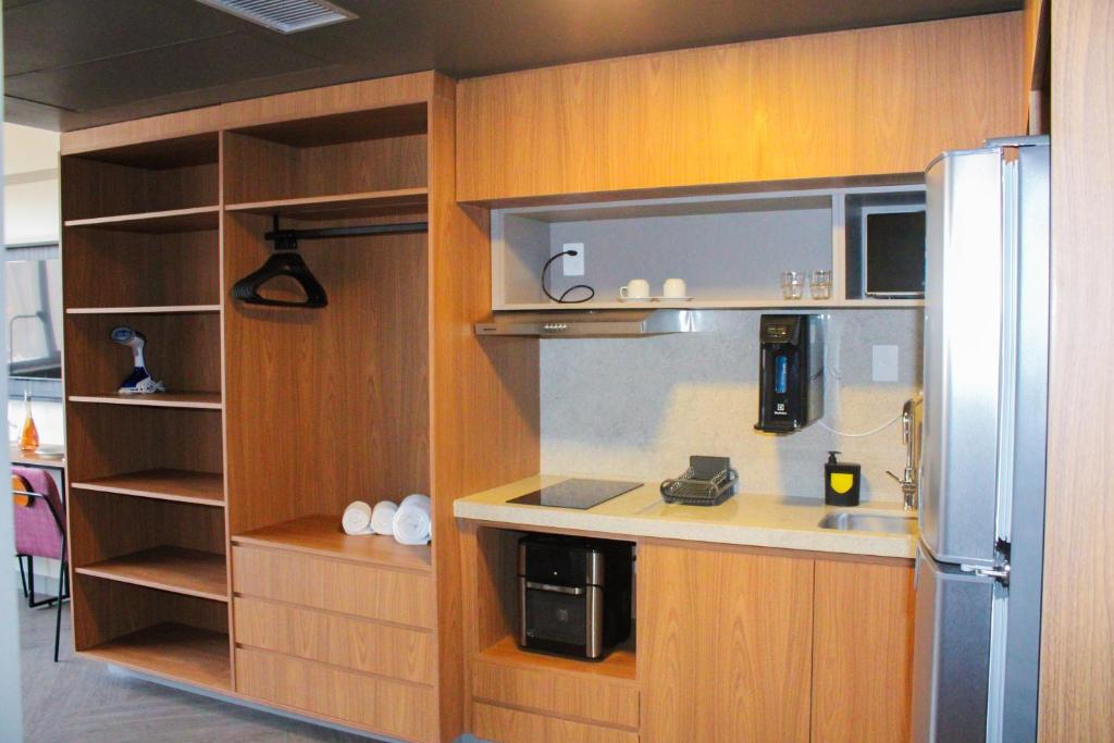 a kitchen with wooden cabinets and a refrigerator at Roomo Transamerica Goiânia Orion in Goiânia