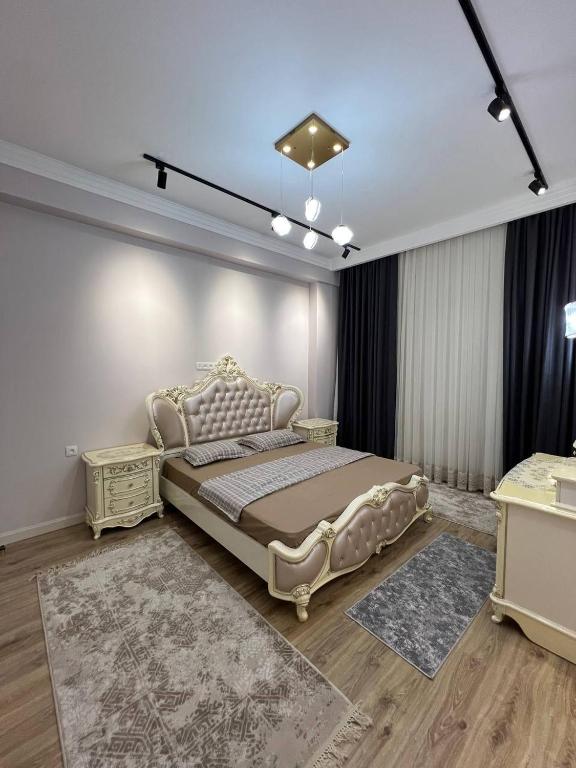 - une chambre avec un grand lit et 2 tables dans l'établissement Tashkent City Apartments E2, à Tachkent