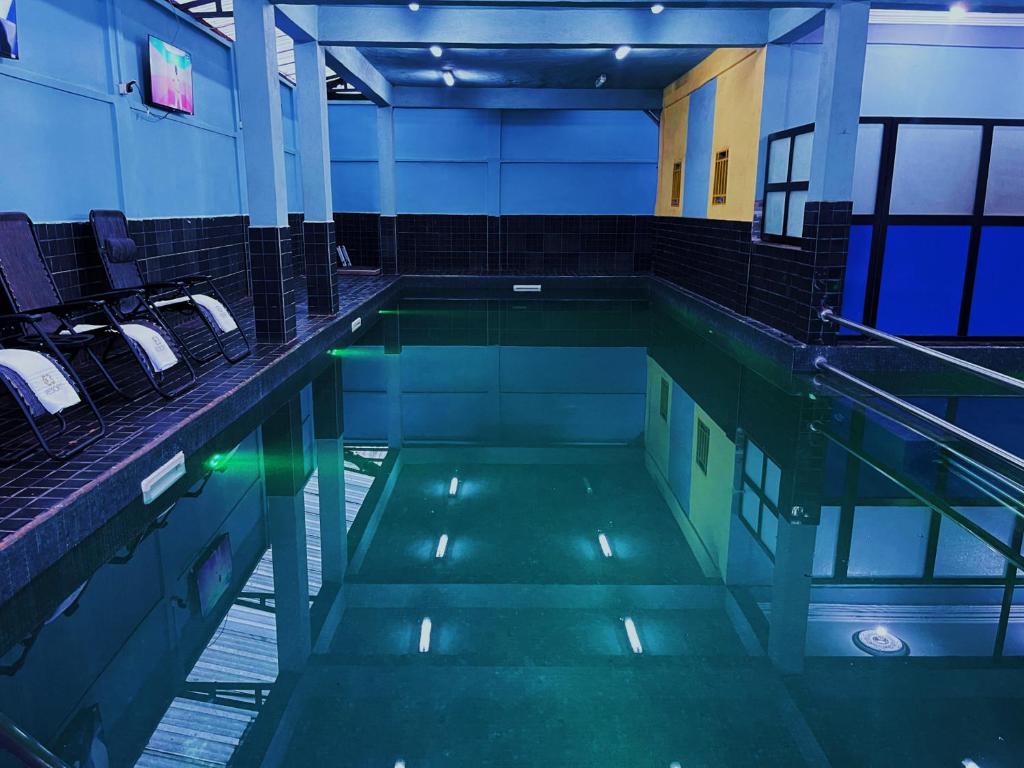 a swimming pool in a building with chairs in it at C3 Resort Hotel Foumbot 