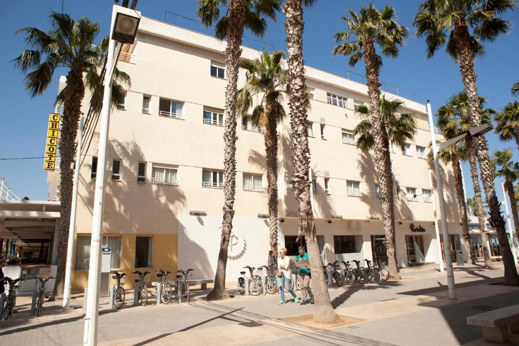 a building with palm trees in front of it at Malvarrosa Beach Rooms in Valencia
