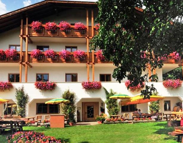 ein großes Gebäude mit Blumen auf den Balkonen und Tischen in der Unterkunft Hotel Mair Am Bach in Brixen
