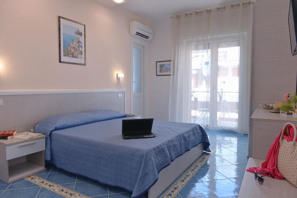 1 dormitorio con 1 cama con ordenador portátil en Acquamarine Maiori Amalfi Coast en Maiori