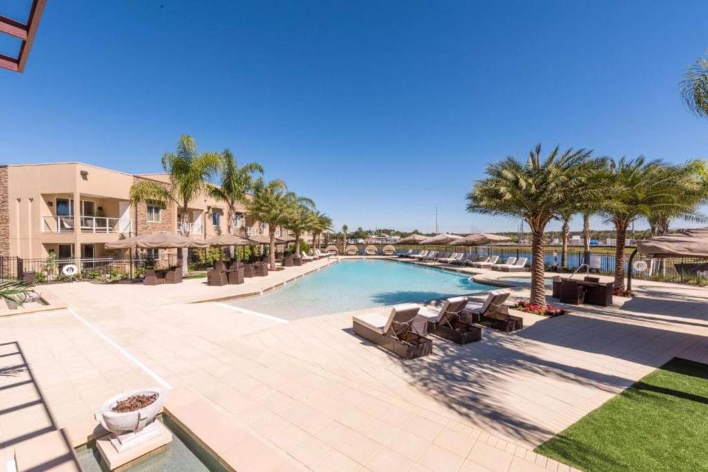 Spacious 4-Suite Villa with Balcony, Magic Village في أورلاندو: وجود مسبح في المنتجع مع الكراسي والنخيل