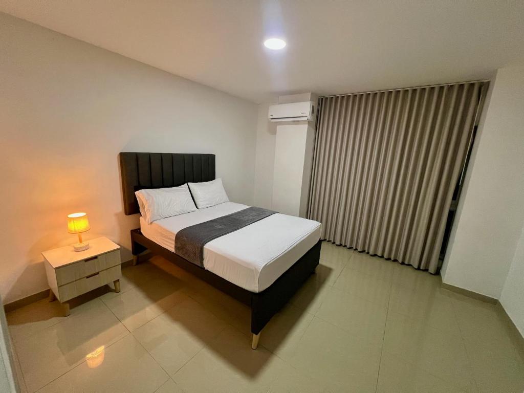 Un dormitorio con una cama y una lámpara en una mesita de noche. en 304 studio apartment in El Peñon, en Cali