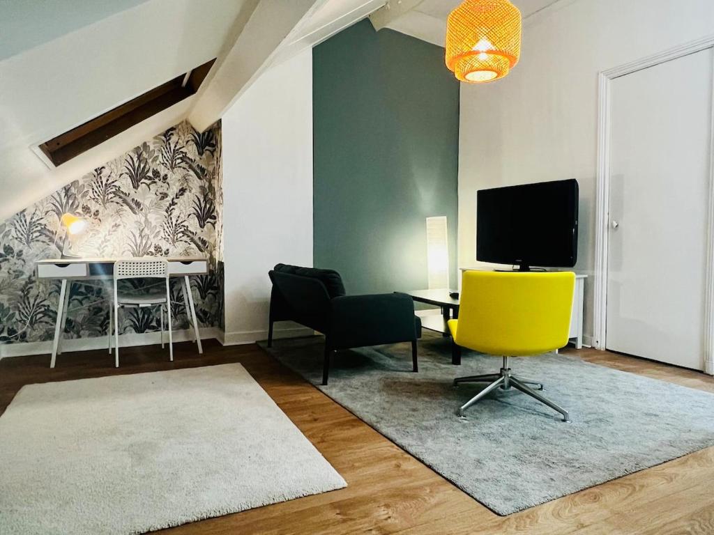 een woonkamer met een tv en een gele stoel bij Appartement calme et spacieux, tout équipé in Saint-Quentin
