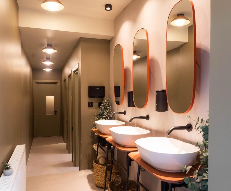 a bathroom with three sinks and mirrors on the wall at Ruby Hostel - Lux Group Dorm Rooms in Kutaisi