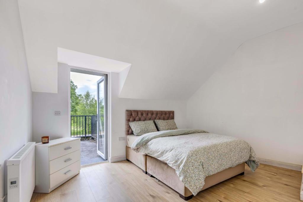 a white bedroom with a bed and a balcony at Rooftop Apartment in Monaghan