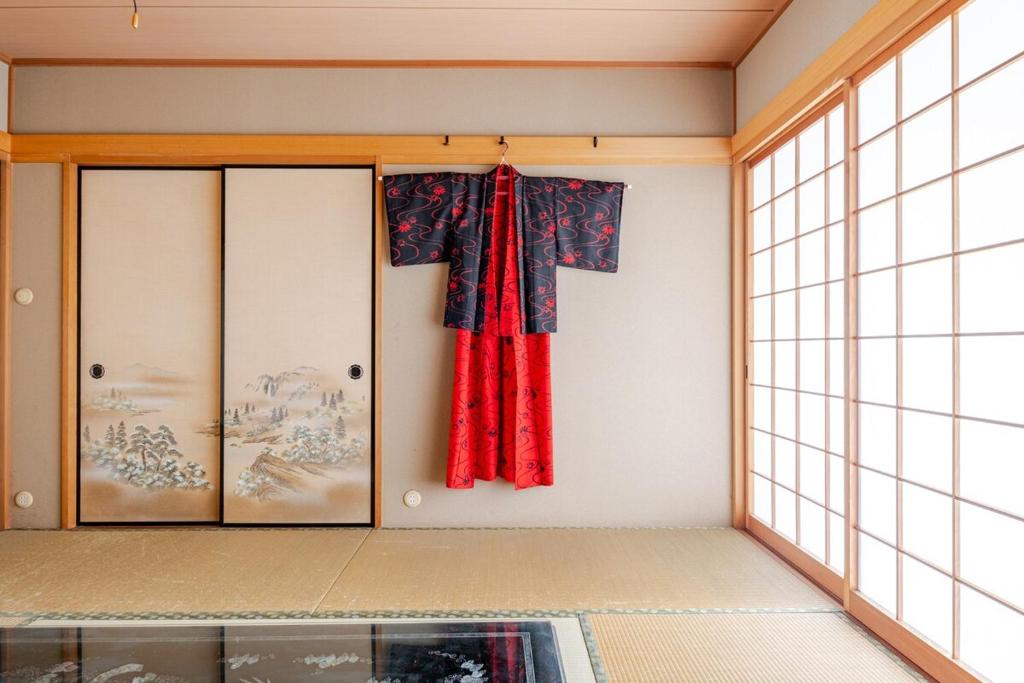 a room with a window and a red curtain at グループ宿泊に最適 Spacious Home Base by Yadoya in Yokkaichi