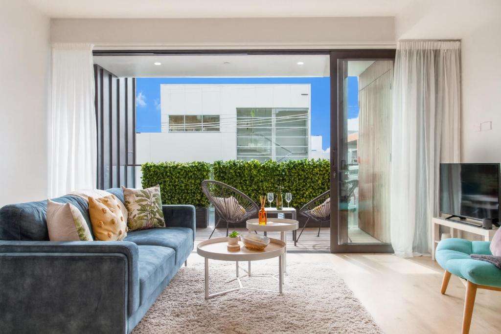 a living room with a blue couch and tables at Walk To Ponsonby and K Road Quiet Home with Blackout Blinds for the perfect sleep in Auckland