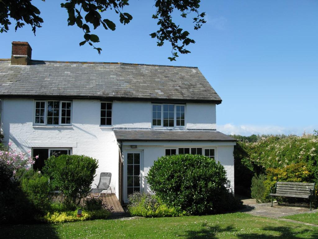 una casa blanca con un banco en el patio en Tollgate Cottages Bed and Breakfast en Freshwater