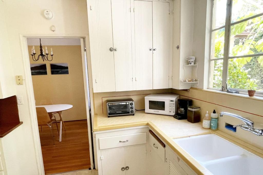 a kitchen with white cabinets and a sink and a microwave at The Marlowe Family Suite in Santa Barbara