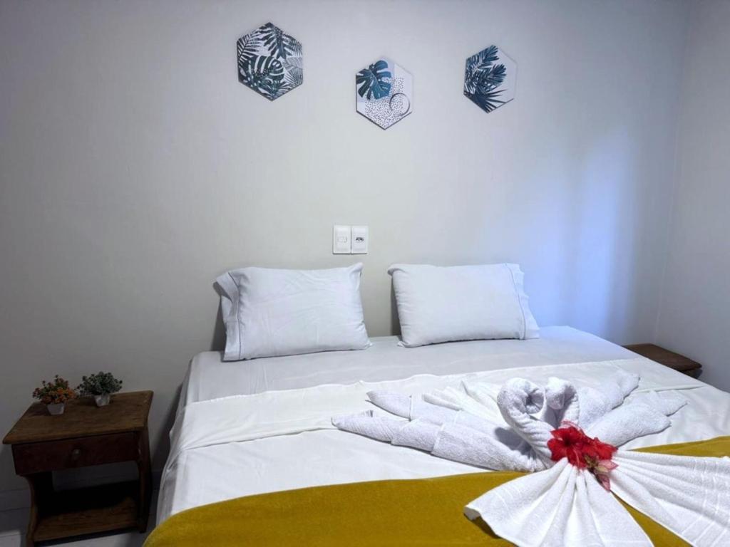 uma cama com lençóis brancos e um laço em Pousada do Trinta em Fernando de Noronha