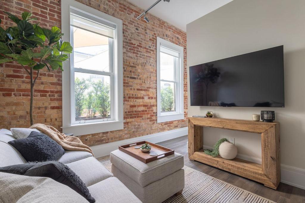 een woonkamer met een bank en een bakstenen muur bij Chestnut Chateau in Baptist Hospital Heliport