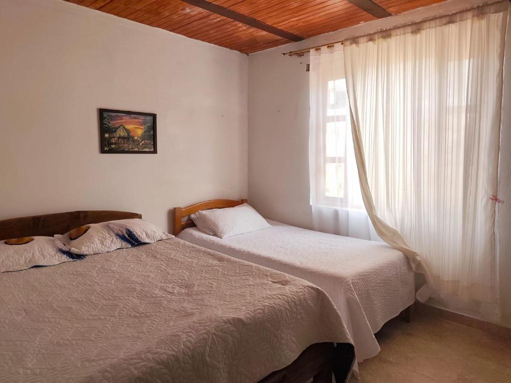 2 Betten in einem Zimmer mit Fenster und einem Bett sidx sidx sidx sidx in der Unterkunft Casa Linda in Villa de Leyva