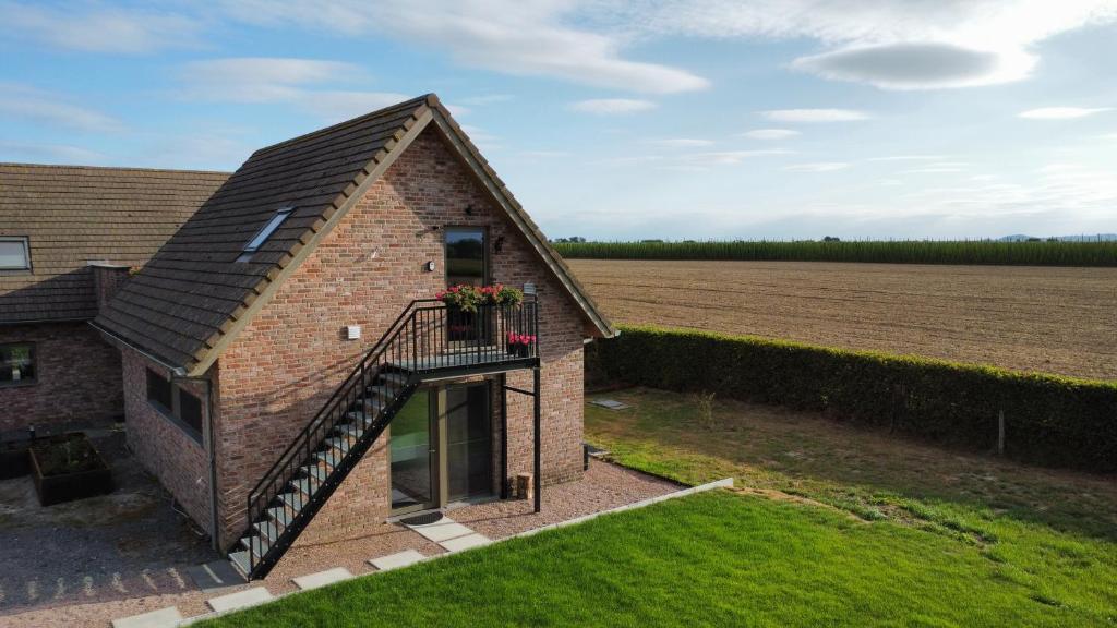 ポペリンゲにあるVakantiewoning De KoeBelleの畑の隣にあるバルコニー付きのレンガ造りの家