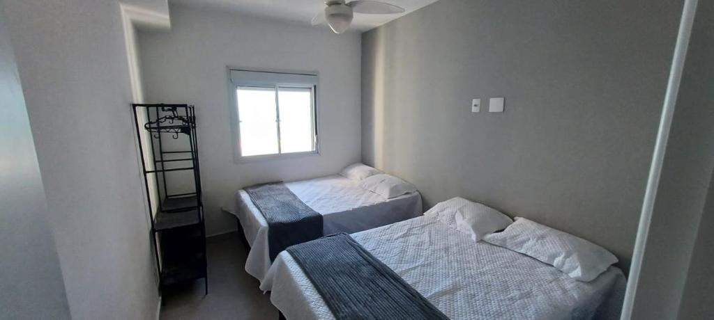 een kleine kamer met twee bedden en een raam bij Ape Condomínio Club - pé na areia in Mongaguá