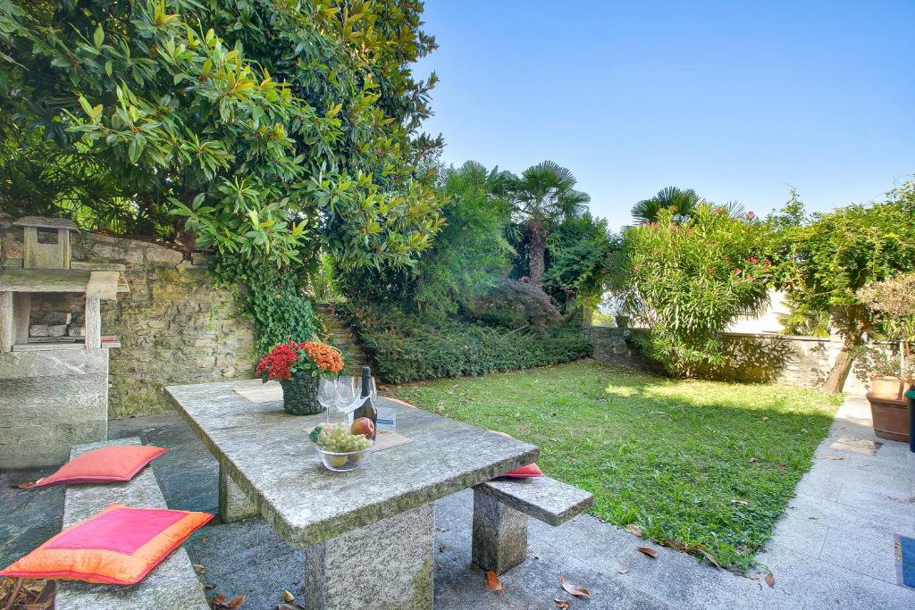 a stone table and chairs in a yard with a garden at Oasi Panoramica con piscina - Happy Rentals in Aldesago