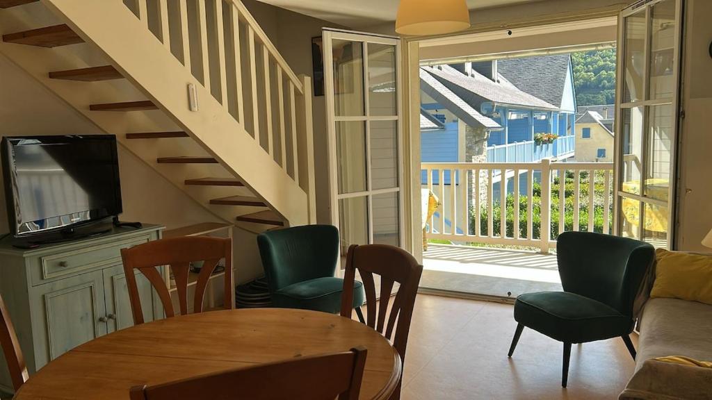 a living room with a table and chairs and a staircase at Appartement au pied de la montagne in Guchen