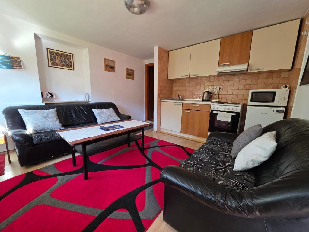 a living room with a black leather couch and a table at Apartment near center in Sarajevo