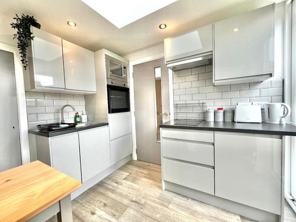 a kitchen with white cabinets and a wooden table at Yastayzzz at Studio 3 Bransford Road in Worcester