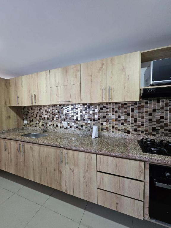 a kitchen with wooden cabinets and a counter top at Magical stay in the pink area of Bello in Bello