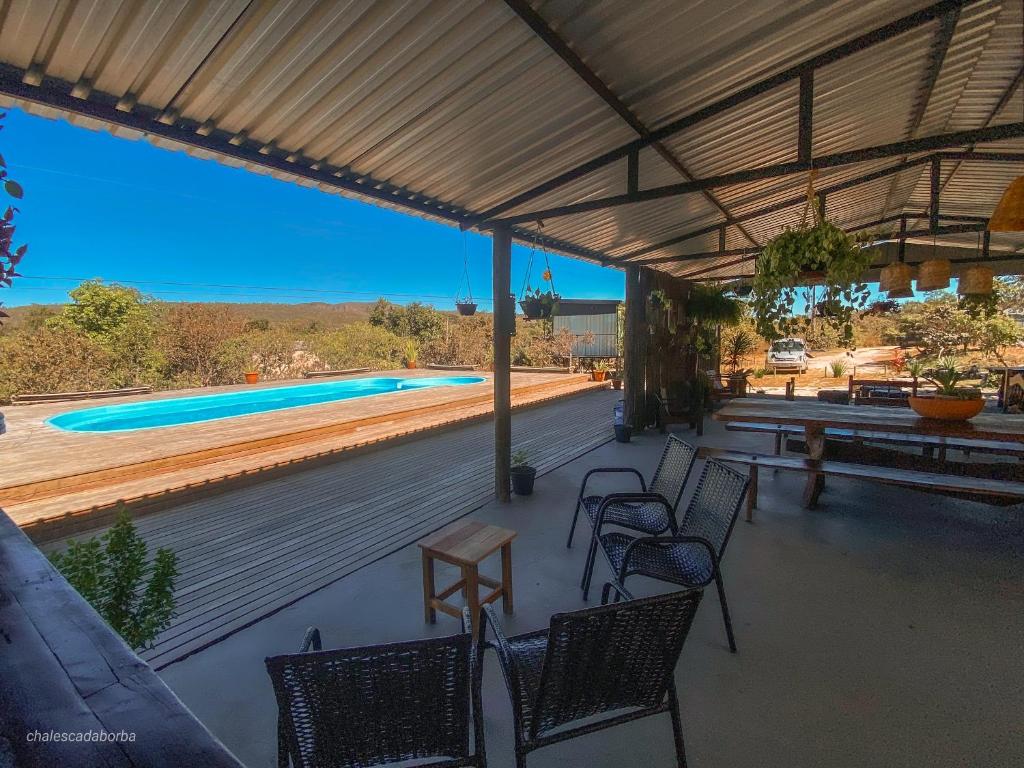 eine Terrasse mit Stühlen, einem Tisch und einem Pool in der Unterkunft Casa Borba Chalé em Alto Paraíso de Goiás in Alto Paraíso de Goiás