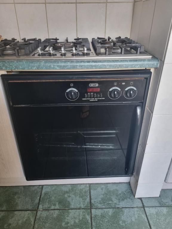 een zwarte oven met kookplaat in een keuken bij Tilde's Self-Catering in Gqeberha